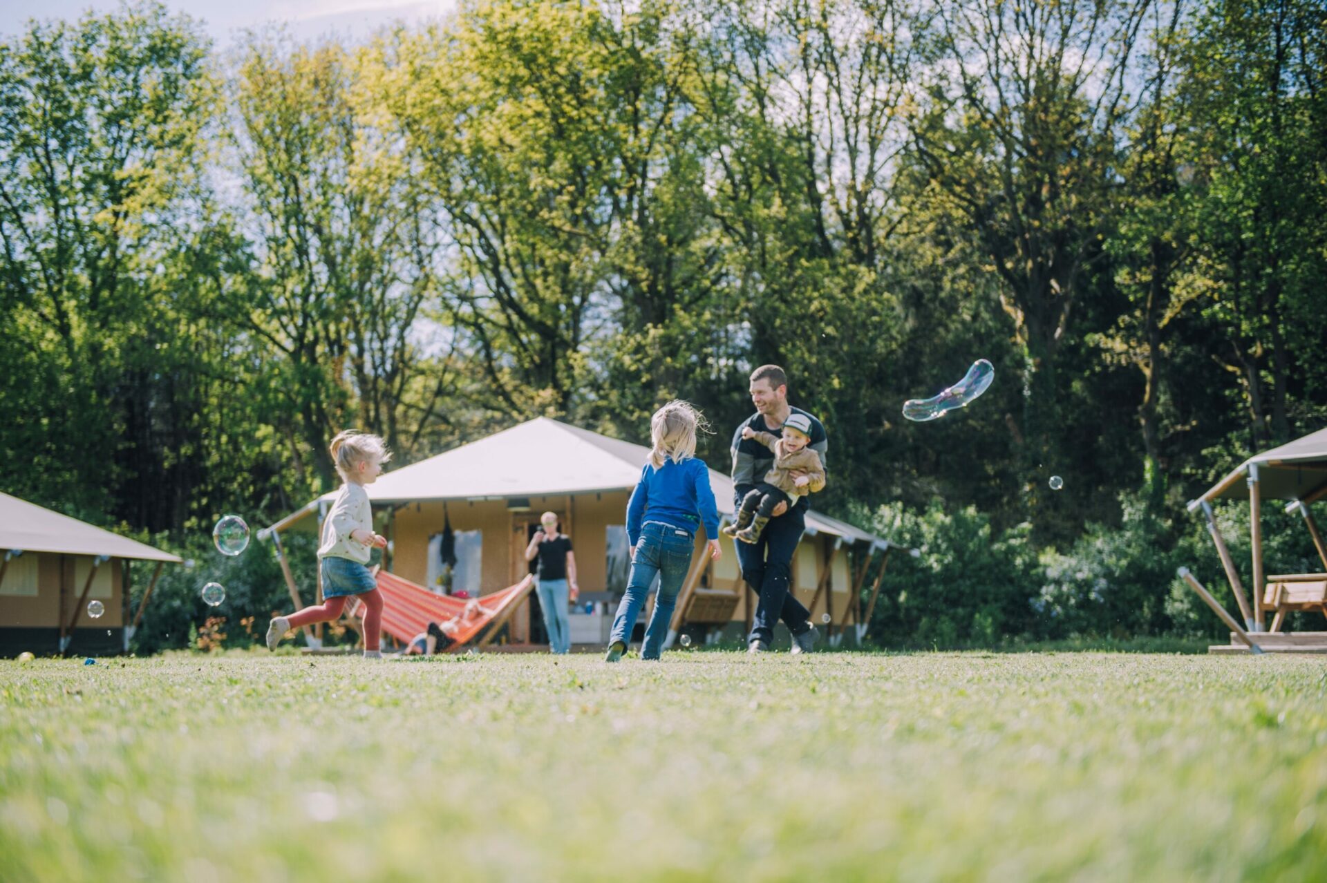 Mega bellen blazen op het veld Gezin blaast mega bellen en speelt samen op het veld bij Glamping de Bosweide